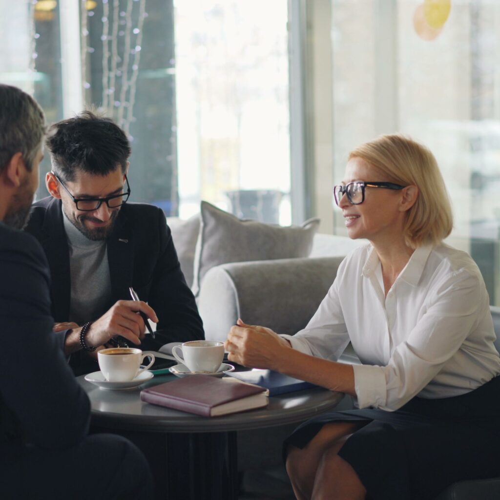 Three professionals engaged in a business meeting at a cafe.